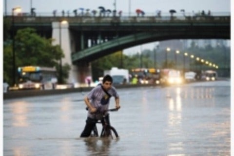 Man on a bike struggles against flooding