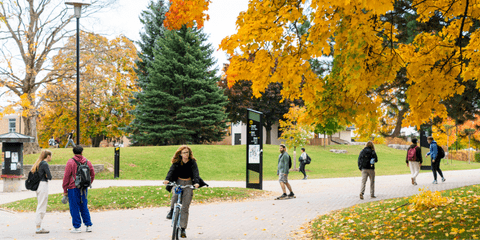 Students biking and walking through main campus in fall