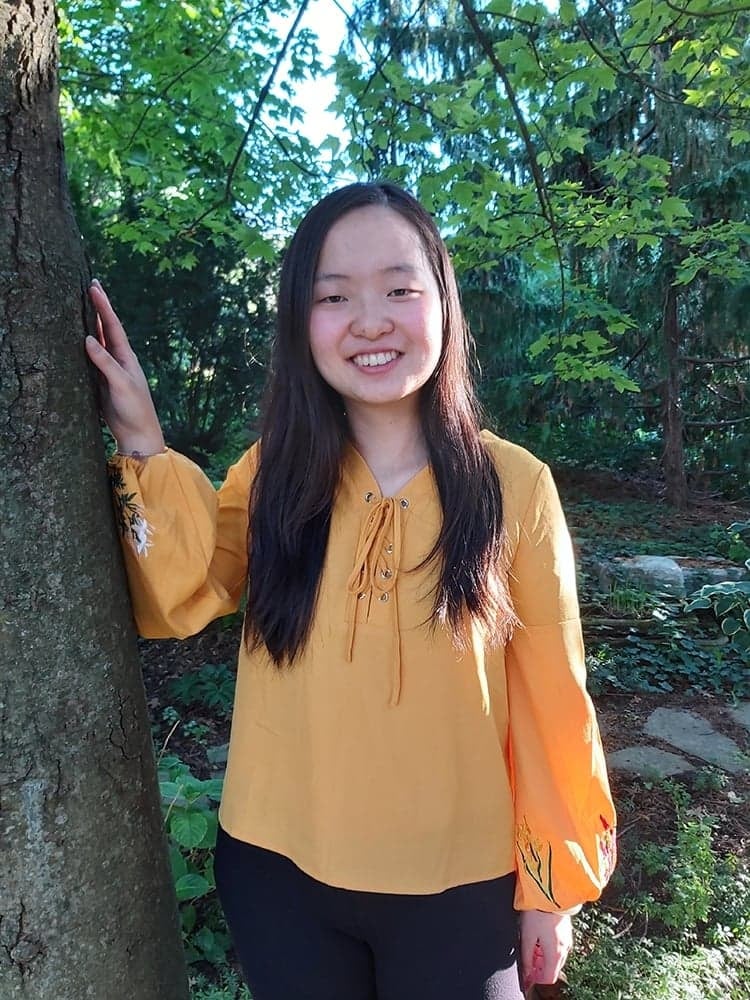 Maggie Chang standing next to tree