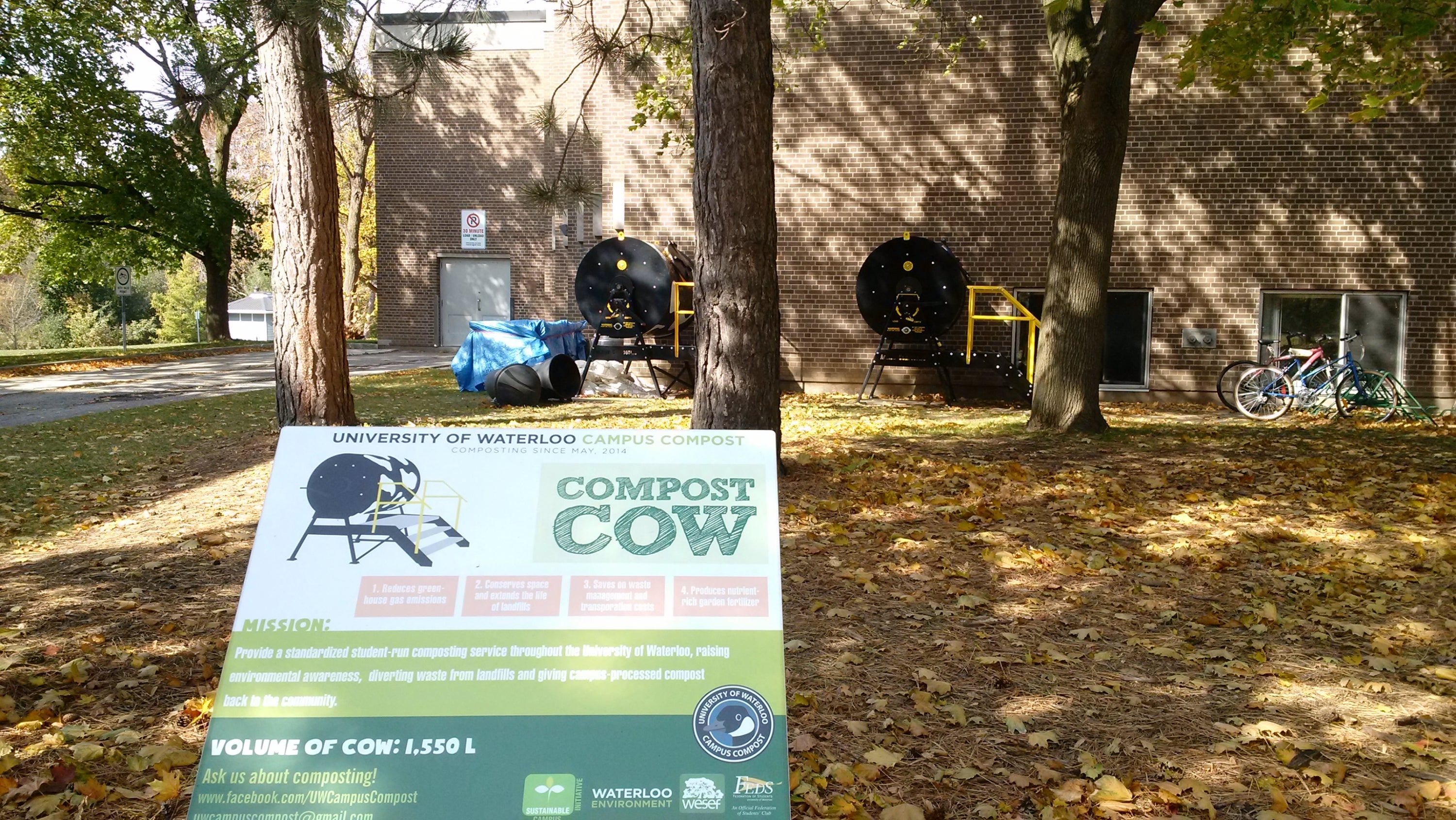 Campus compost sign with compost cows in background