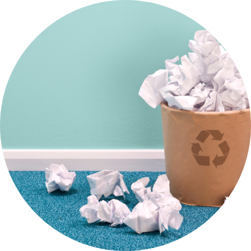 Recycling bin with crumpled up balls of paper in bin and on floor