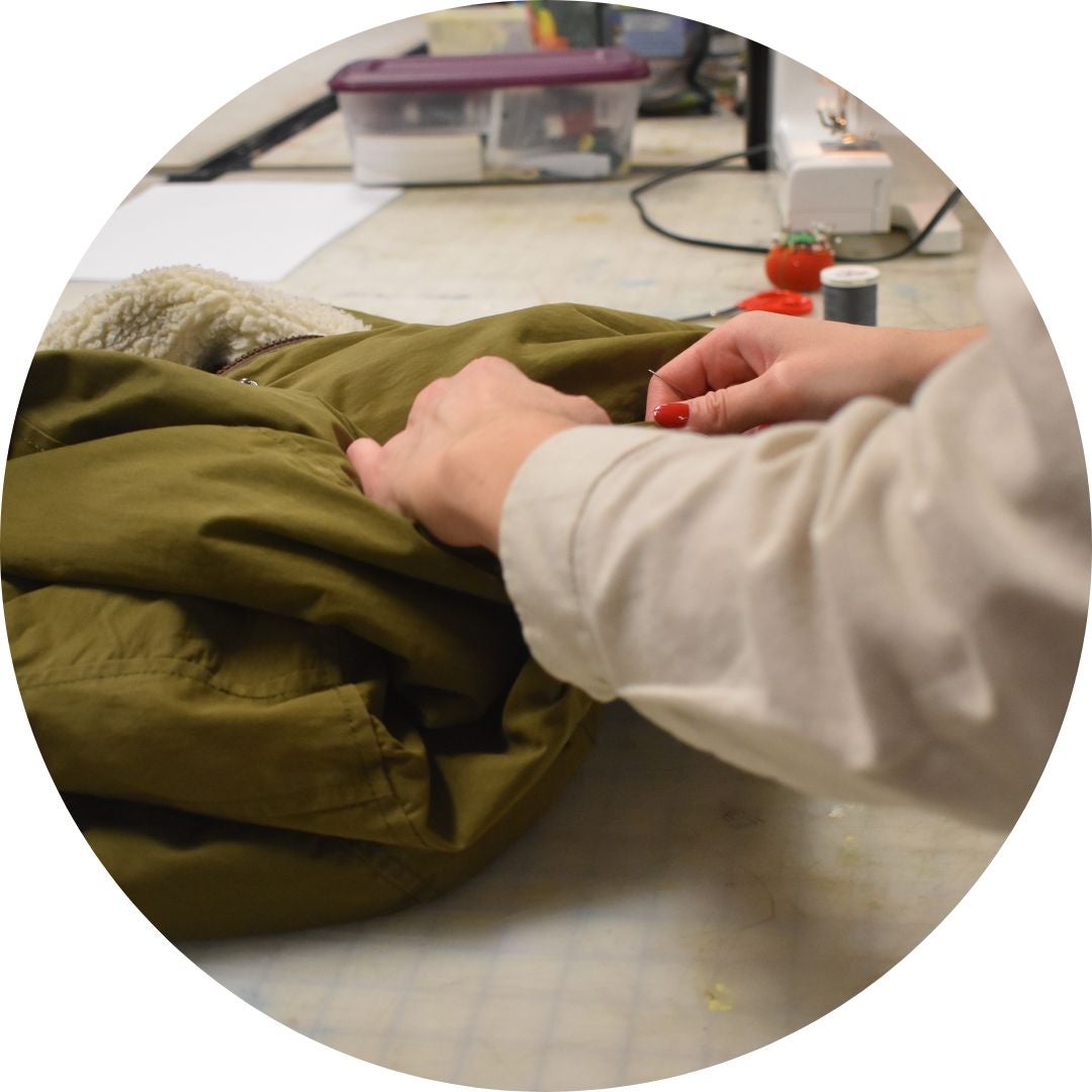 Seamstress repairing coat at repair workshop