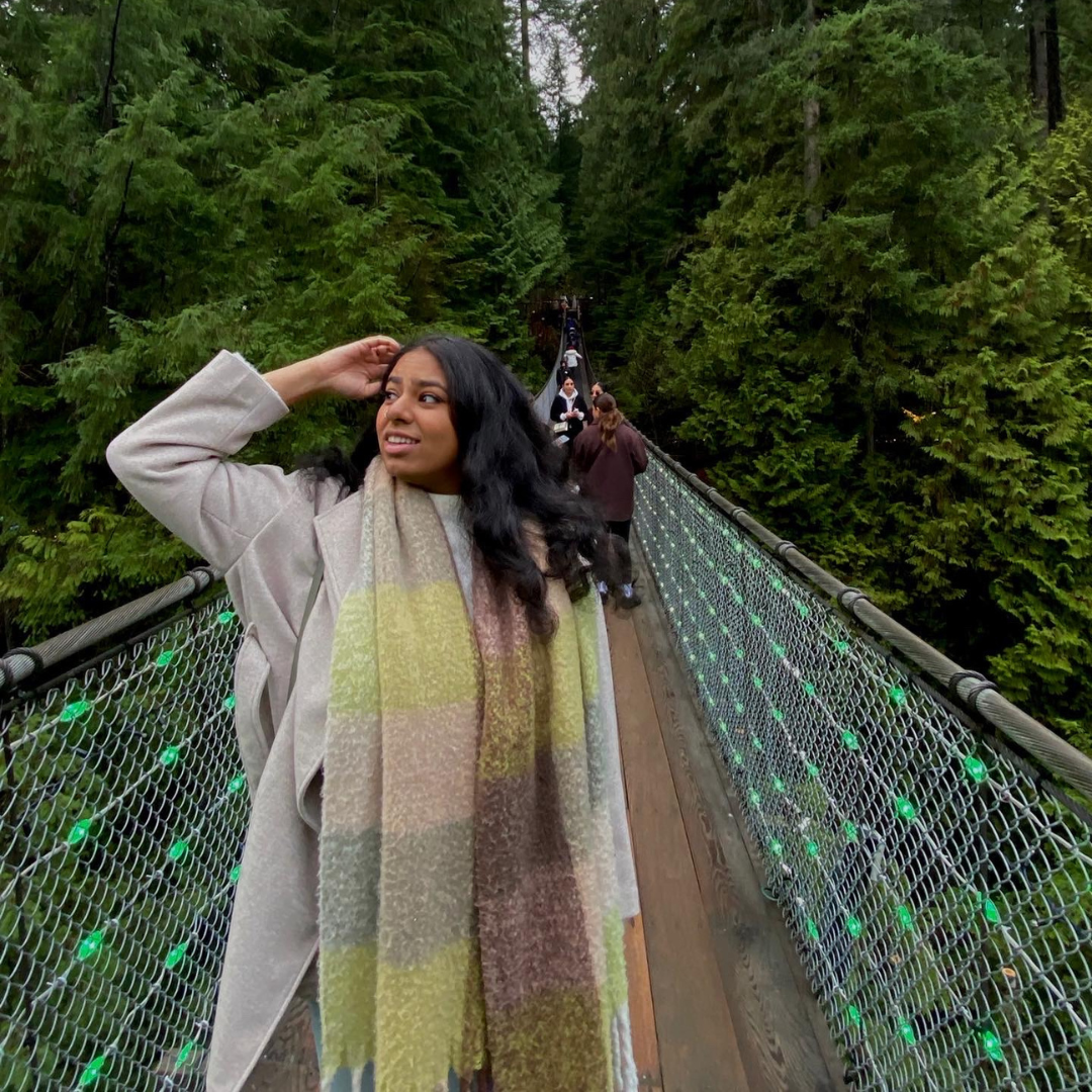 Shreya standing on a bridge in a forest. 