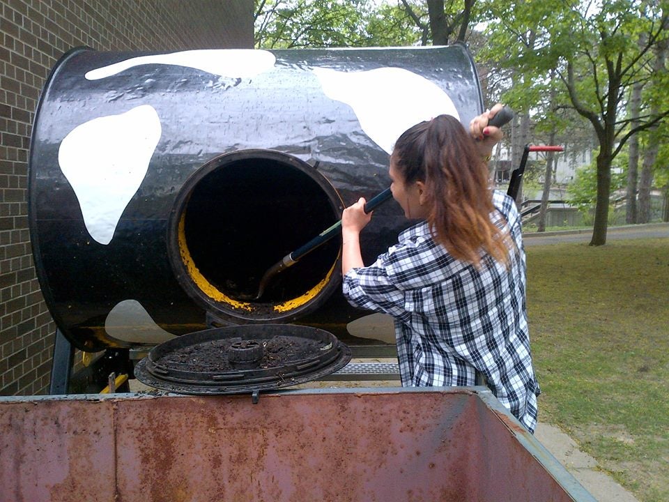 Student emptying composted material from compost tumbler