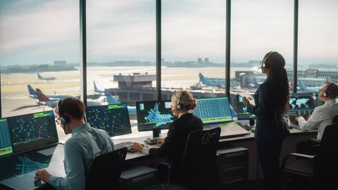 Air traffic controllers monitor screens and coordinate aircraft movements, ensuring aviation safety from a control room