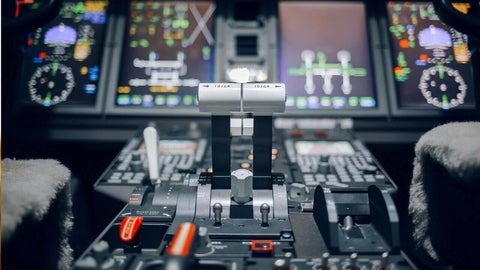 An image of an airplane's cockpit focussing on throttles in the centre. 