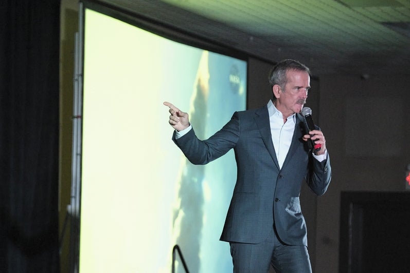 Commander Chris Hadfield pointing at a screen on stage