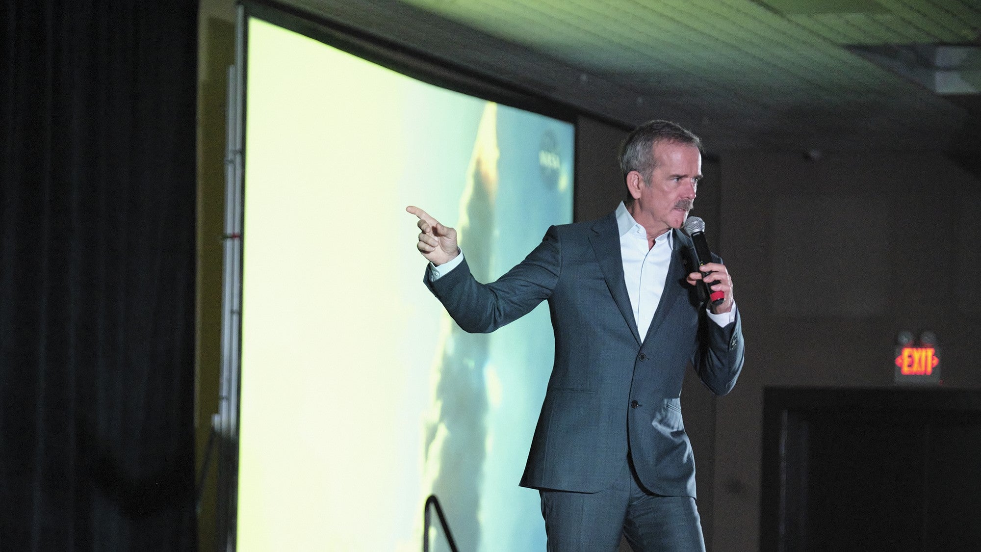 Commander Chris Hadfield pointing at a screen on stage