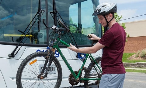 A cyclist mounts his bike to a designated rack on the front of a GRT bus.
