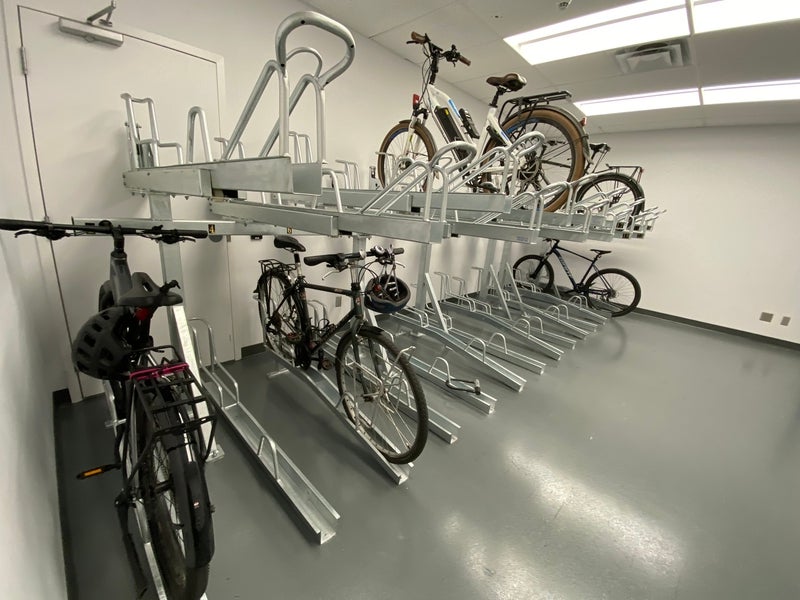 An indoor room showing tiered bike racks with bikes parked in a few of them.