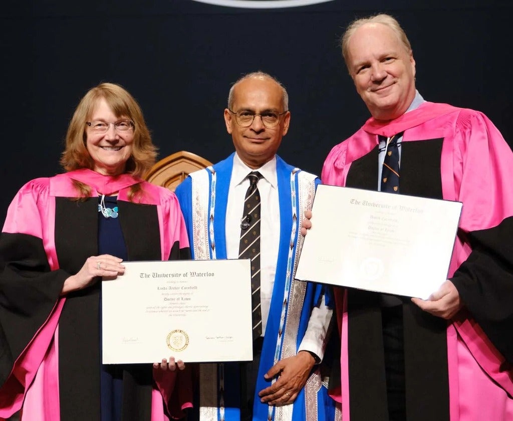 Linda Archer Cornfield and David J. Cornfield accepting their honorary doctorates on stage with President Vivek Goel.