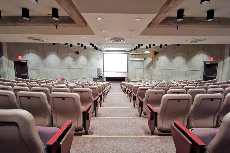 Room with multiple tiers of lecture-style seating and bright track lighting.