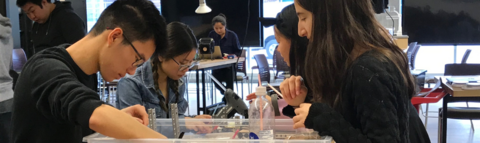 Students build something together, seated at a table