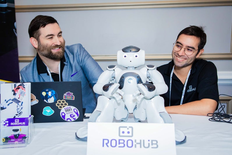 Two men sitting and smiling with a robot