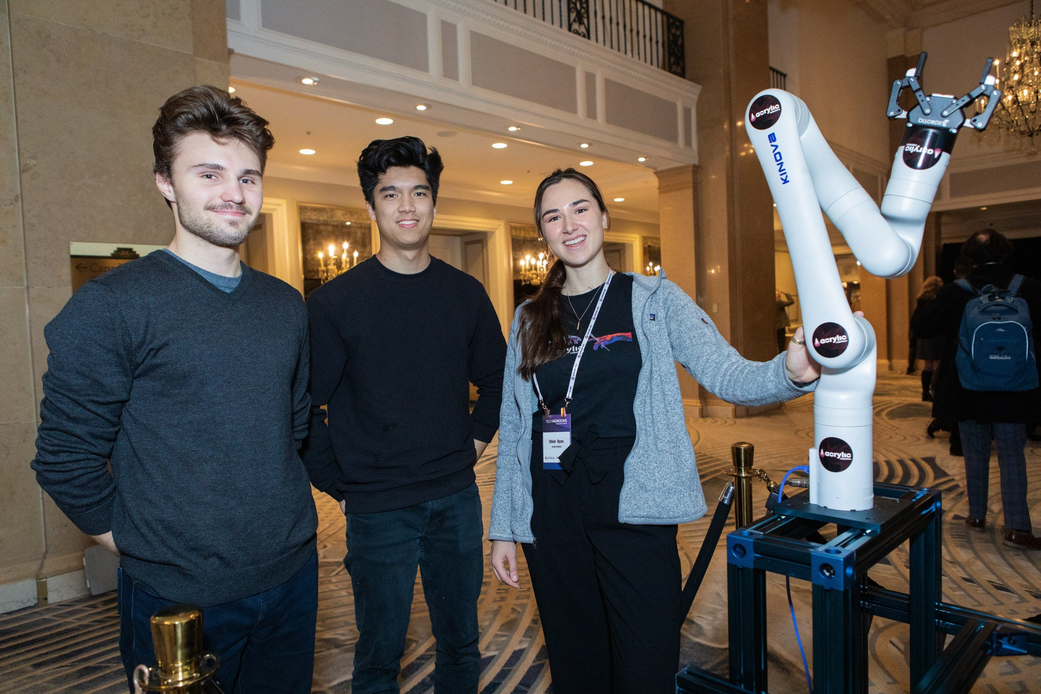 A team posing with a robot arm