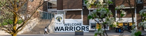 Welcome Warriors sign outside of South Campus Hall in spring with blooming trees