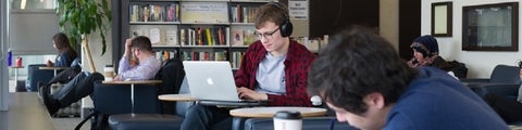 Student studying in a lounge with a MAC computer