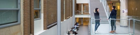 Two students standing at the bottom of a staircase in the Science Teaching Complex