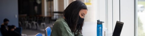 Student studying in a mask with a laptop