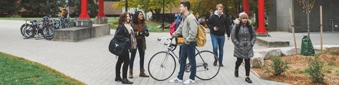 Student with a bike socializing with other students