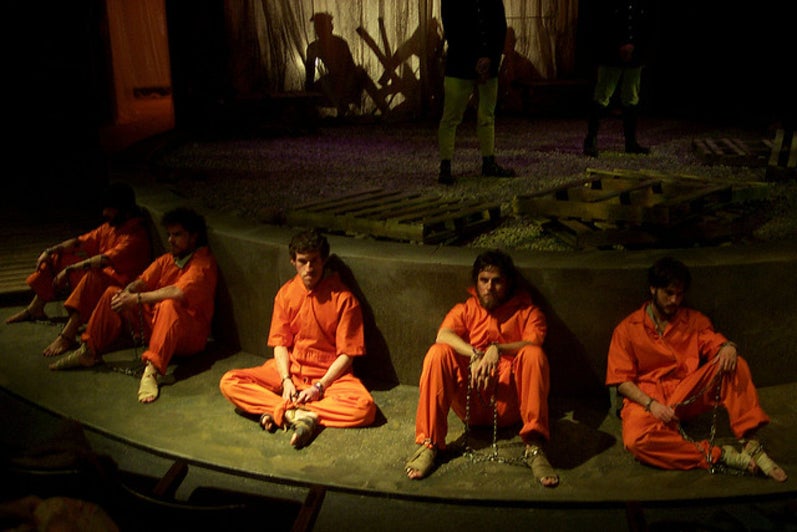 Group of men sitting in prison uniforms