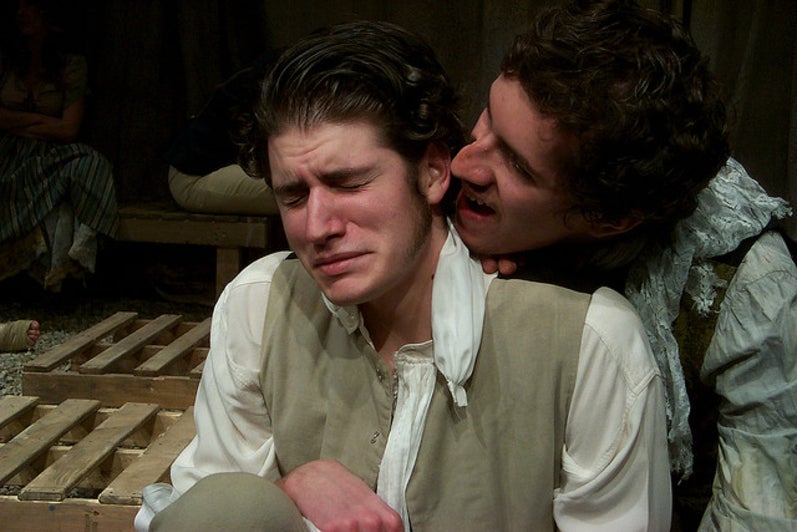 Man speaking over the shoulder of another man who looks scared