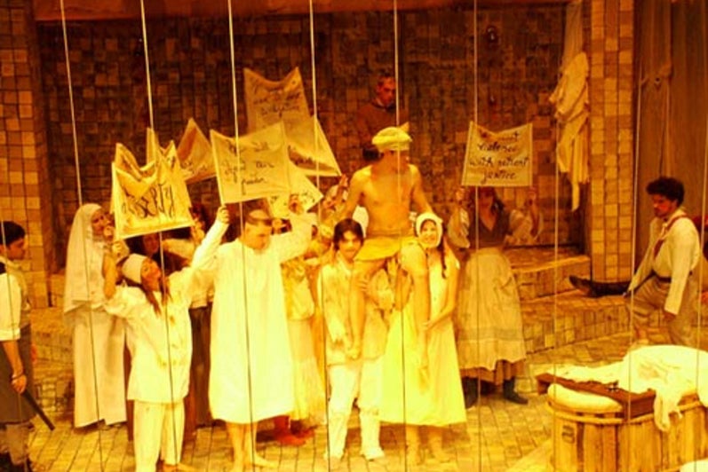 Cast of Marat/Sade holding signs on stage