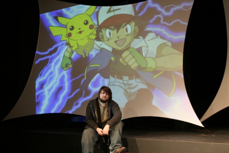 Boy sitting with Pokemon on screen behind him