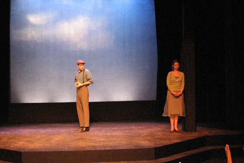 Man looking over his shoulder at a woman on stage