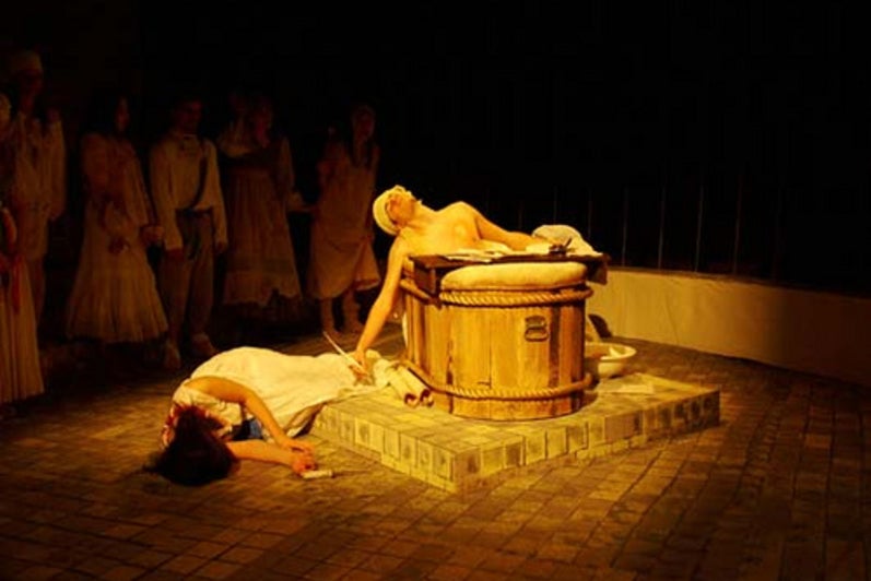 Man in bath tub and woman acting dead on stage