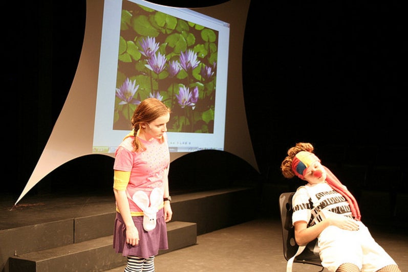 Girl looking at another girl with a clown nose in the play Alice (Experiments) In Wonderland