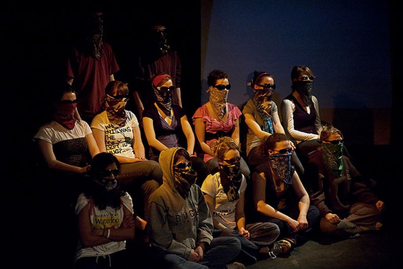 Group of people sitting with sunglasses and bandannas covering their faces