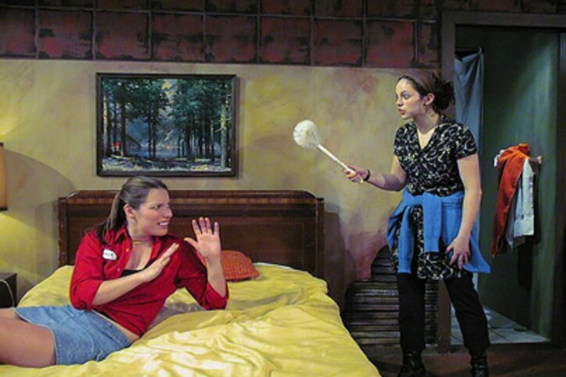 Woman threatening another woman on a bed with a dust brush