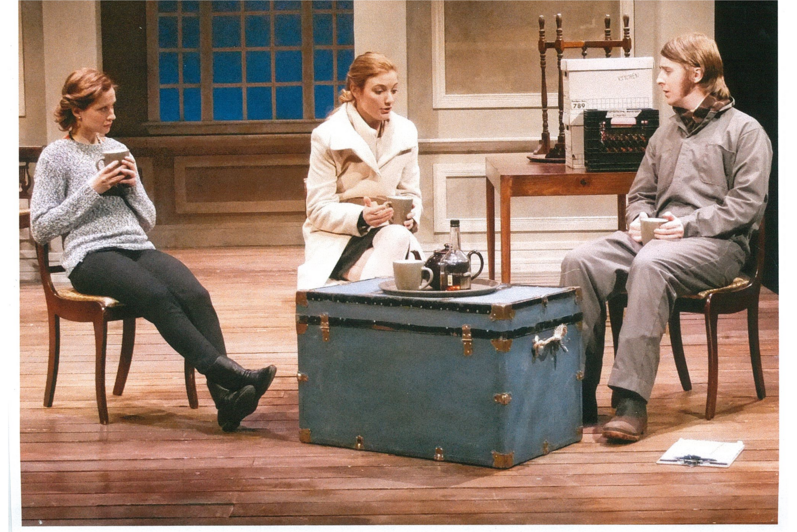 Two women and a man sitting down drinking from mugs 