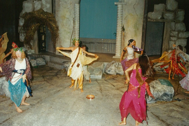 Eight people in colourful clothing dancing