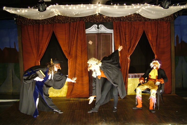 Actors in masks facing each other and bowing 