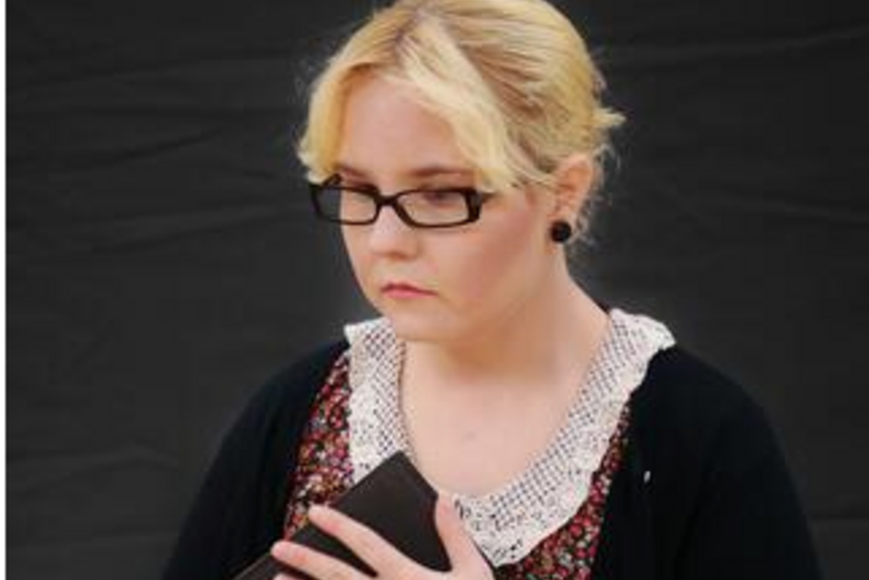 woman holding book against her chest.