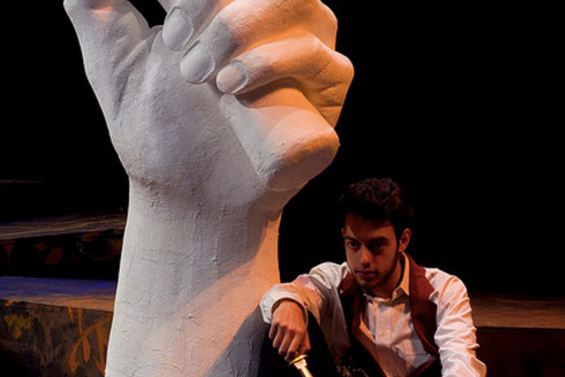 Man sitting holding knife in the play 'Julius Caesar'