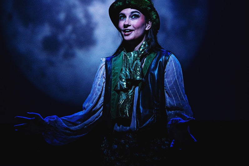 Puck (Daniela Milicevic) assures the audience that the play's events were but a dream, while a large moon looms in the background.