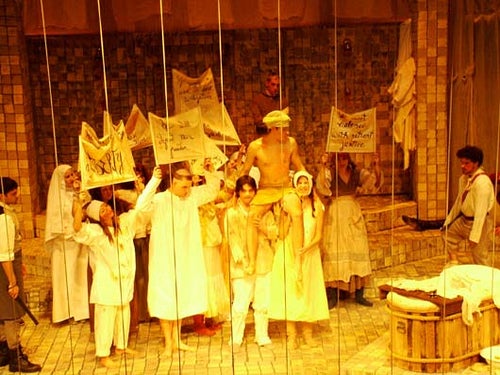 Cast of Marat/Sade holding signs on stage