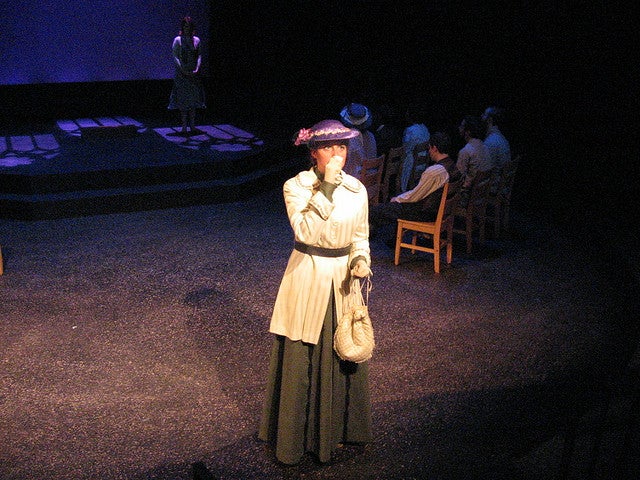 Woman standing on the stage with a group sitting in the background