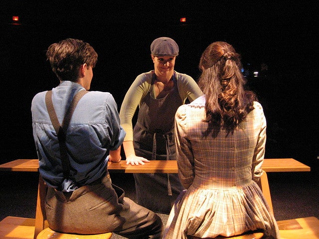 Woman talking to a man and a woman who are sitting down