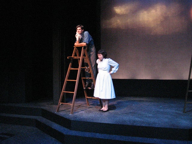 Man on a ladder on stage with a woman