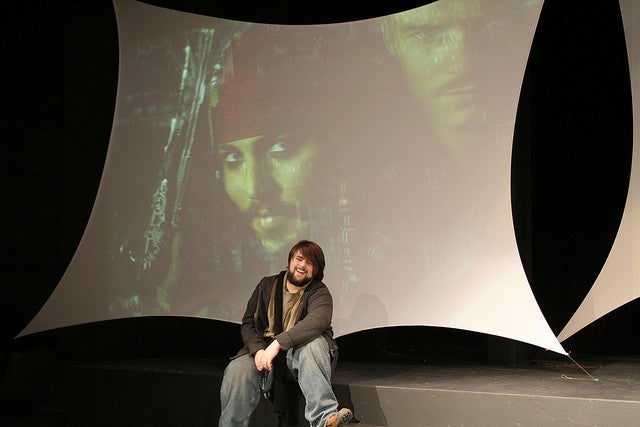 Boy sitting with Pirates of the Caribbean on screen behind him