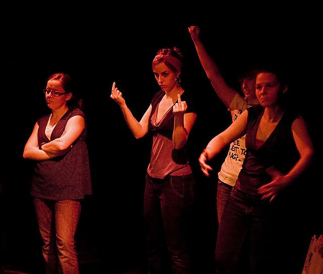 Girl holding up her middle fingers with others standing be her side in the play Differ/End: The Caledonia Project