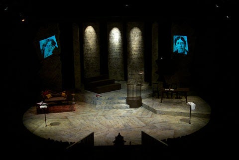 Picture of the stage for Gross Indecency with two faces being shown on screens