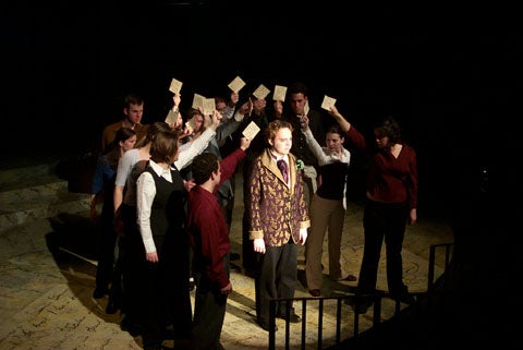 Group of people holding pieces of paper above a man in the center