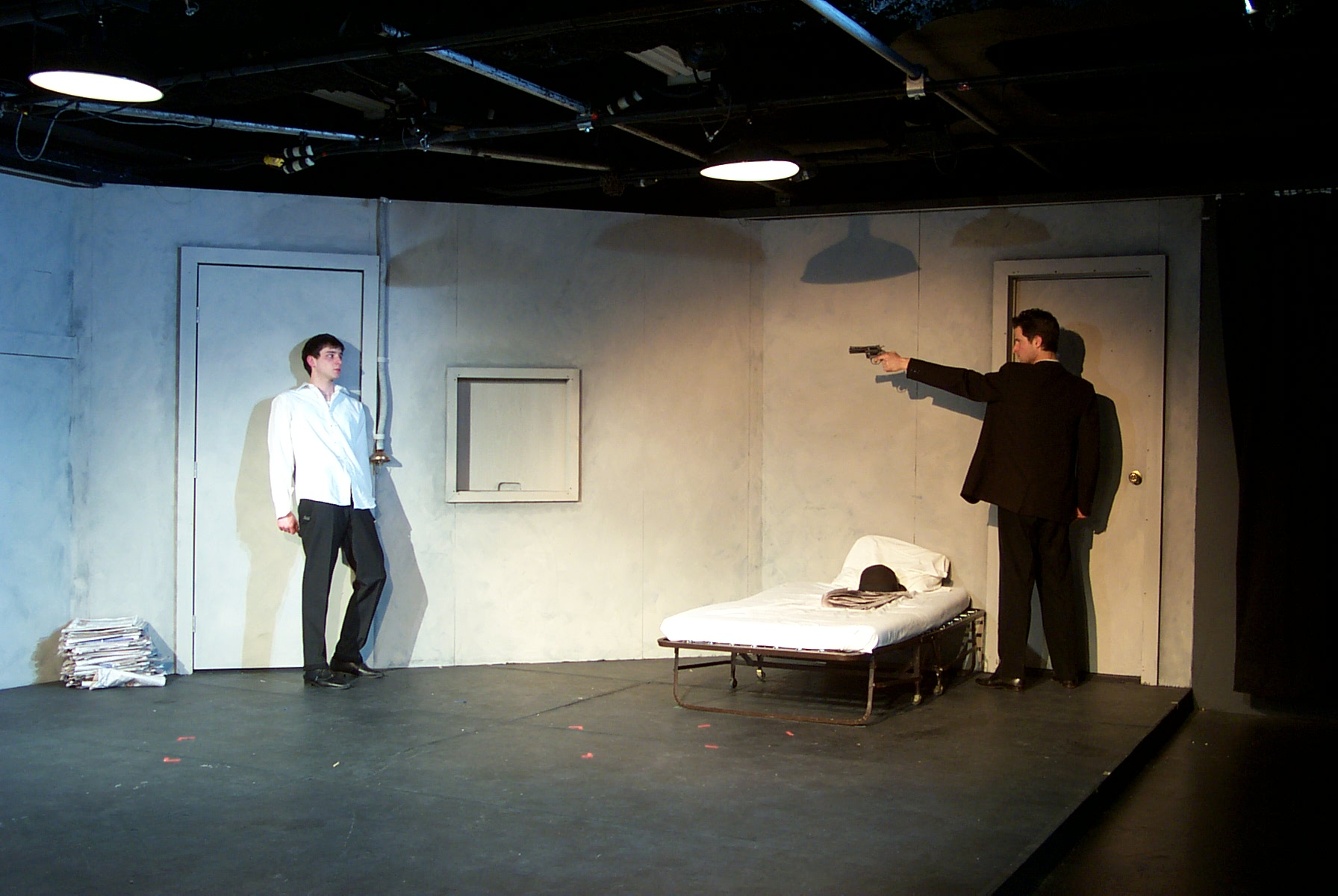 Man in black suit pointing gun at man in white dress shirt