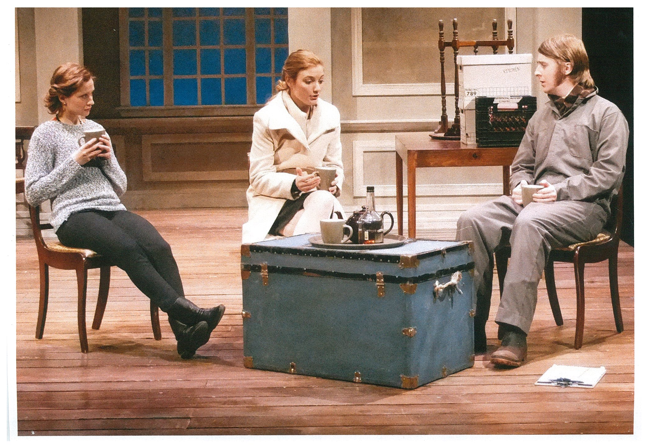 Two women and a man sitting down drinking from mugs 