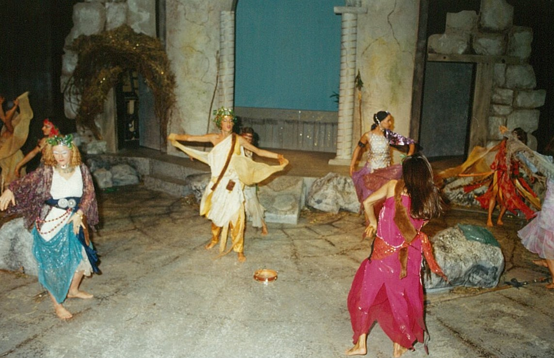 Eight people in colourful clothing dancing
